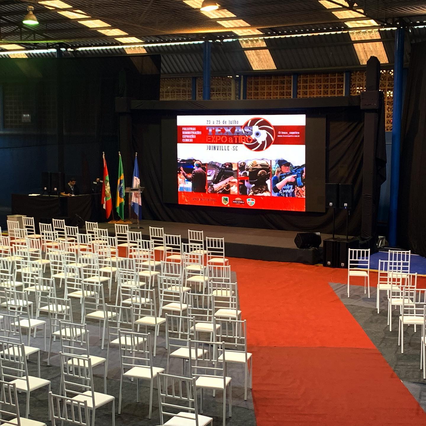 Palco de evento corporativo com telão e cadeiras dispostas para o público